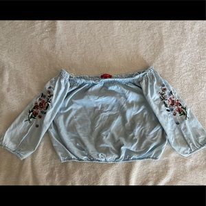 Blue off shoulder crop top with flower embroidery.
